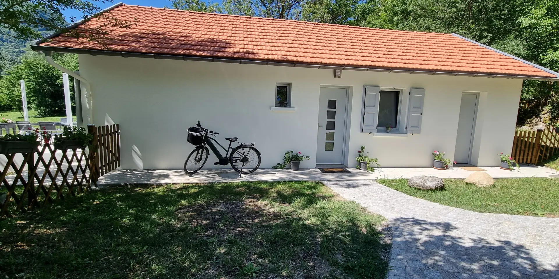 Maison blanche avec vélo noir devant et clôture en bois