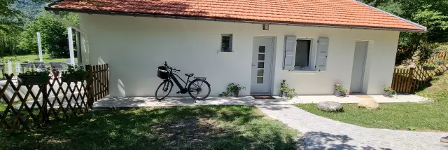 Maison blanche avec vélo noir devant et clôture en bois