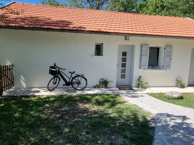 Maison blanche avec vélo noir devant et clôture en bois