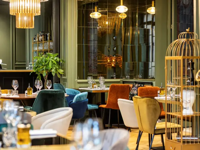 Intérieur d'un restaurant avec des chaises colorées, des tables bien dressées et des décorations lumineuses