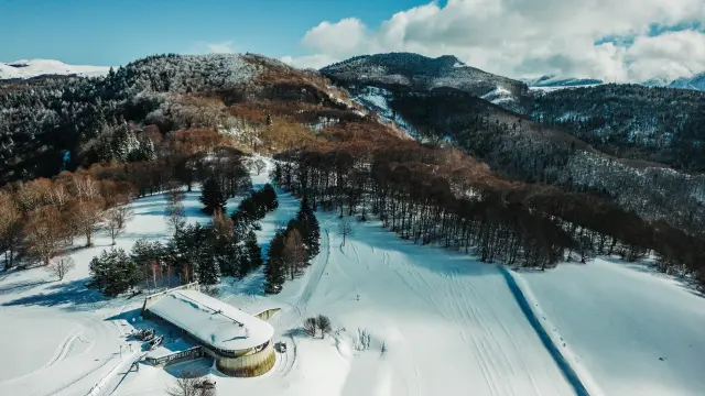 Vue aérienne d'une station de ski avec des pistes enneigées et des montagnes en arrière-plan