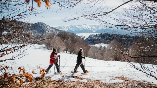 Deux personnes faisant de la randonnée en raquettes dans un paysage enneigé