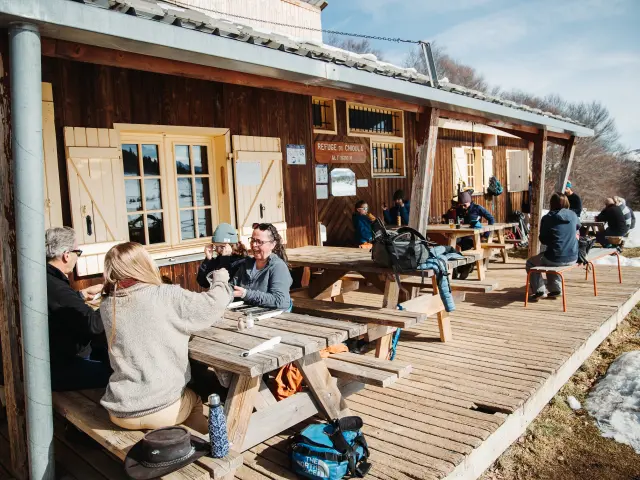 Groupe de personnes assises à des tables en bois devant un chalet en hiver