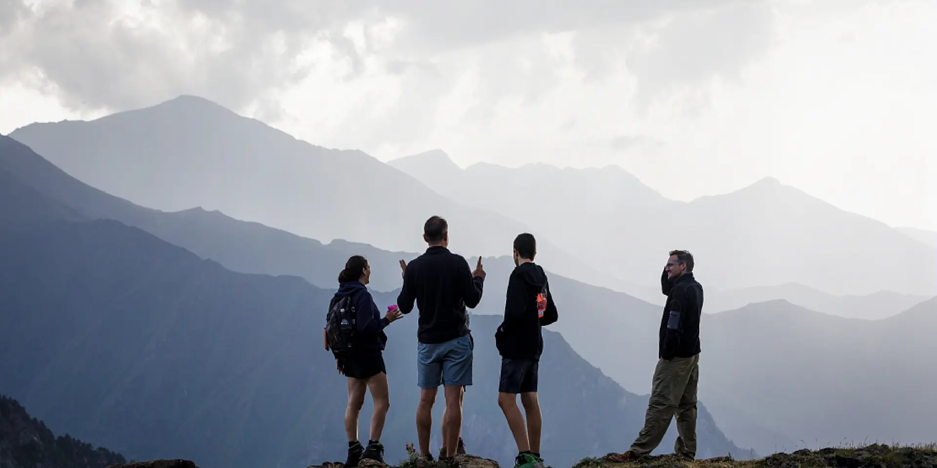 Quatre randonneurs debout sur une crête, admirant les montagnes