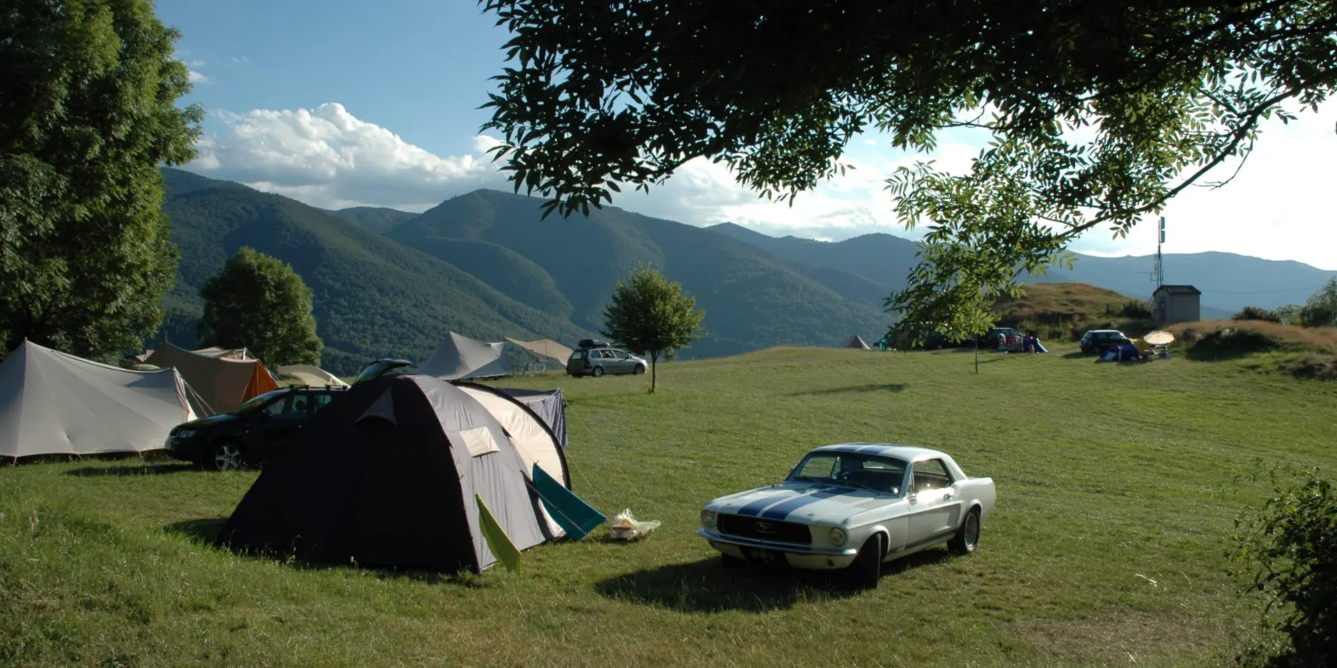 Tente et voiture dans un camping en pleine nature avec vue sur les montagnes