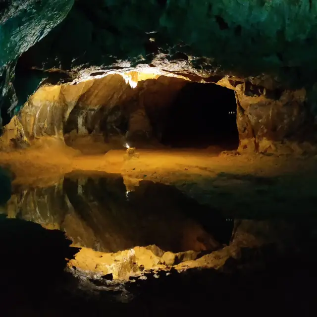 Grotte éclairée avec des reflets dorés sur l'eau