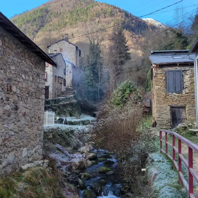 Un ruisseau coule à travers un village de montagne avec des maisons en pierre