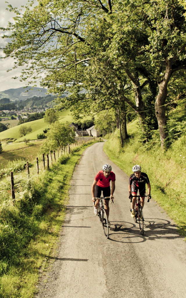 Deux cyclistes montent par une route de campagne