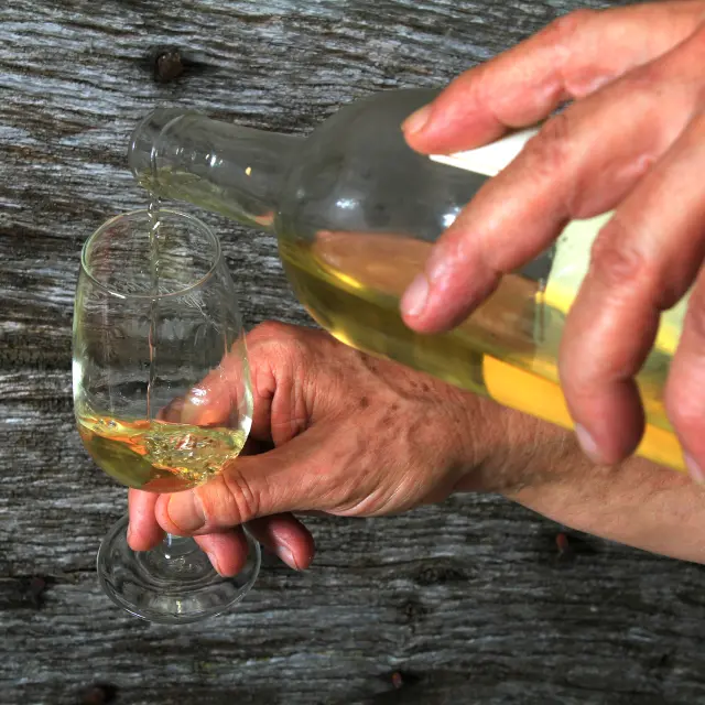 Deux mains servent du vin du Clos Guirouilh à Lasseube