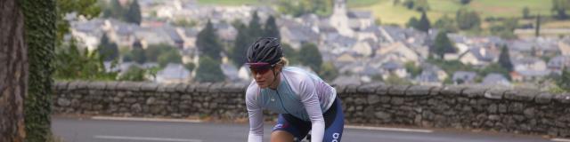 Une cycliste sur la route, village en arrière plan