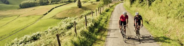 Deux cyclistes montent par une route de campagne