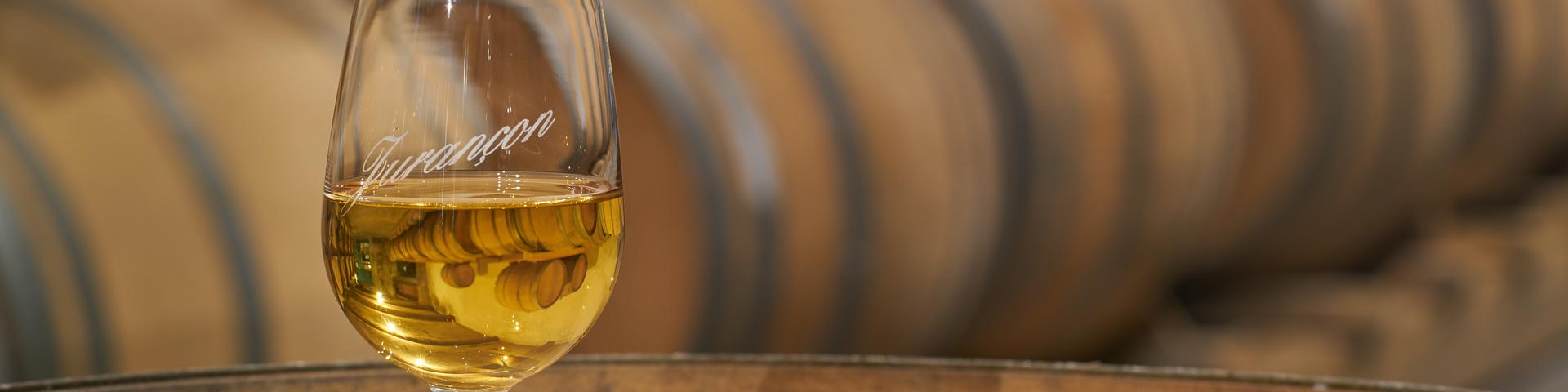 Un verre de vin de Jurançon est posé sur un tonneau dans un chai