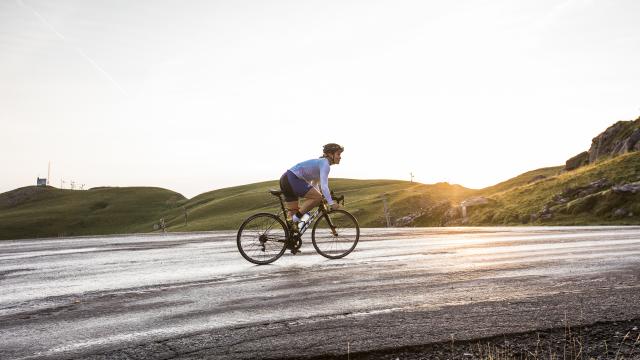 Une cycliste sur la route au coucher du soleil