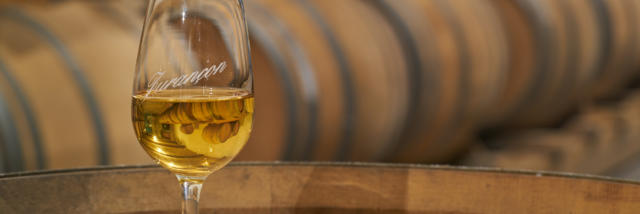 Un verre de vin de Jurançon est posé sur un tonneau dans un chai