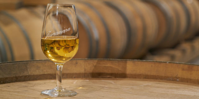 Un verre de vin de Jurançon est posé sur un tonneau dans un chai