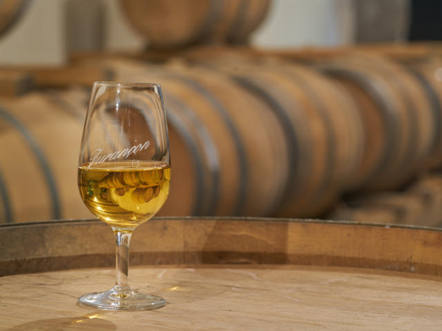 Un verre de vin de Jurançon est posé sur un tonneau dans un chai