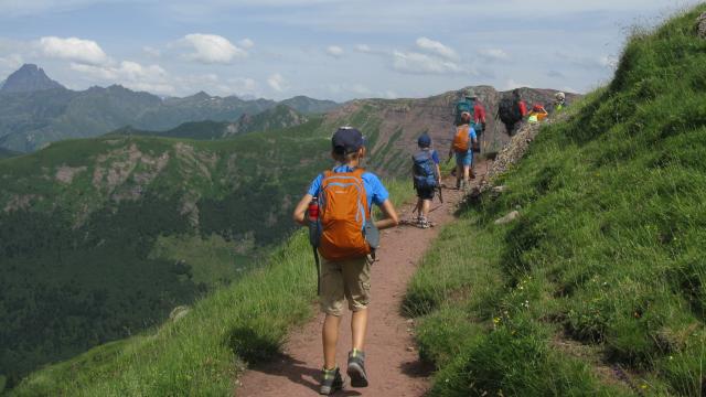 Sur le sentier du col de Saoubathou (vallée d’Aspe), on suit le guide géologue en marchant sur des roches rouges. Au fond, l’Ossau (Pyrénées béarnaises)