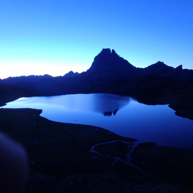 Lever de soleil pour les géorandonneurs sur la terrasse du refuge d’Ayous : en vedette, le pic du Midi d’’Ossau et son reflet dans le lac l (Pyrénées béarnaises)
