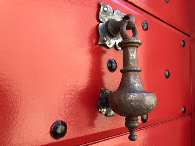 Aldabón antiguo sobre una puerta roja