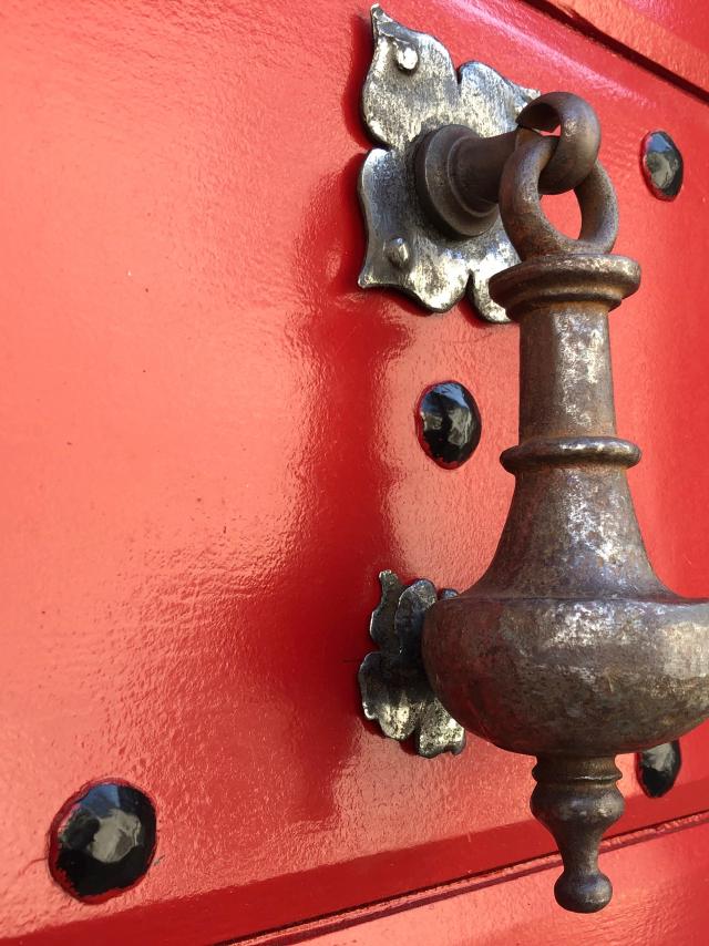 Aldabón antiguo sobre una puerta roja