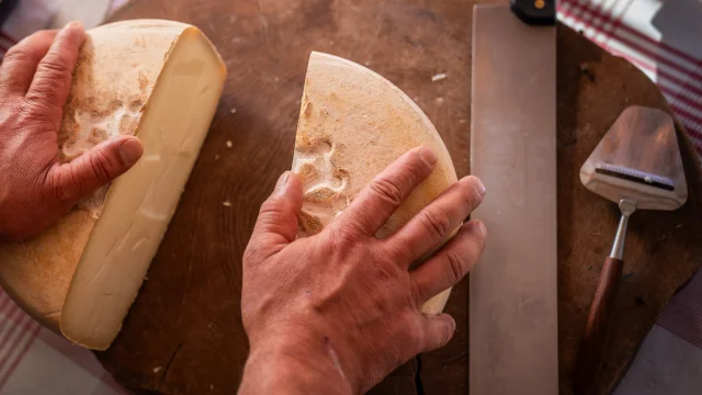 fromage coupé en deux sur un plateau en bois qui est posé sur une table