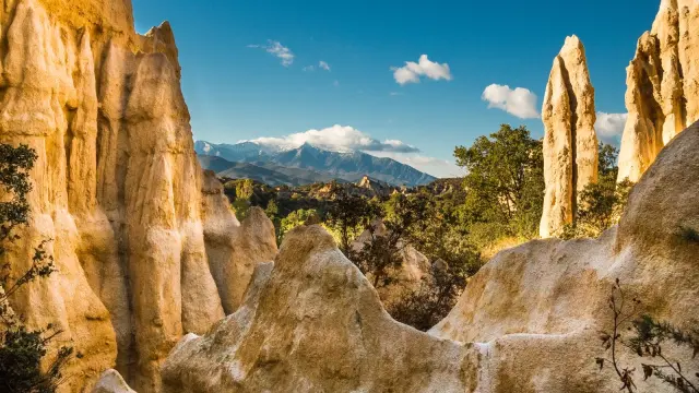 Formations rocheuses des orgues d’Ille-sur-Têt dans les Pyrénées-Orientales, avec vue sur le massif du Canigó enneigé sous un ciel bleu.