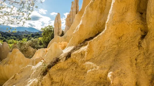Les orgues d’Ille-sur-Têt dans les Pyrénées-Orientales, formations naturelles de sable et d’argile sculptées par l’érosion, sous un ciel bleu et un soleil éclatant.