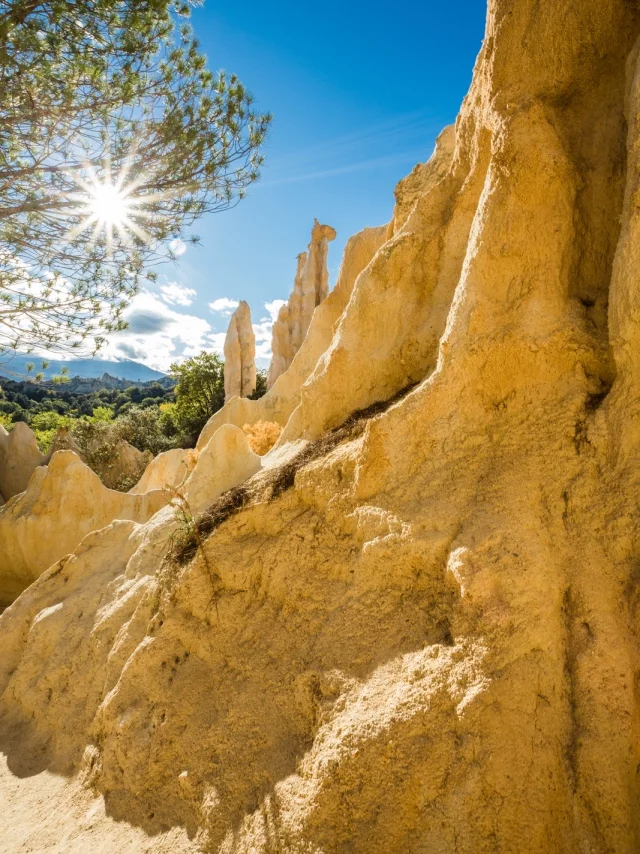 Les orgues d’Ille-sur-Têt dans les Pyrénées-Orientales, formations naturelles de sable et d’argile sculptées par l’érosion, sous un ciel bleu et un soleil éclatant.