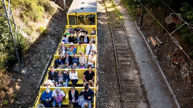 Wagon découvert du Train Jaune rempli de voyageurs profitant du trajet à travers les montagnes catalanes.