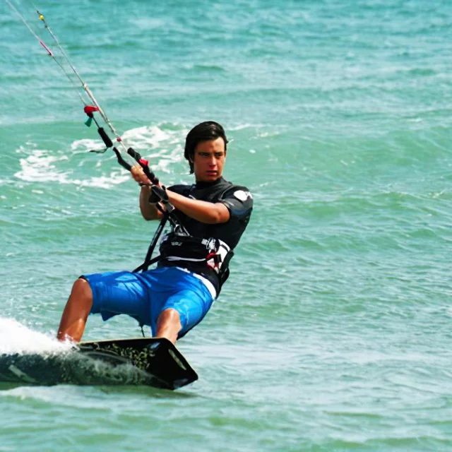Personne pratiquant le kitesurf sur une mer turquoise par temps ensoleillé.