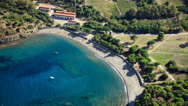 Vue aérienne de la crique de Paulilles dans les Pyrénées-Orientales, avec sa plage de galets bordée d’eaux turquoise et entourée de verdure.