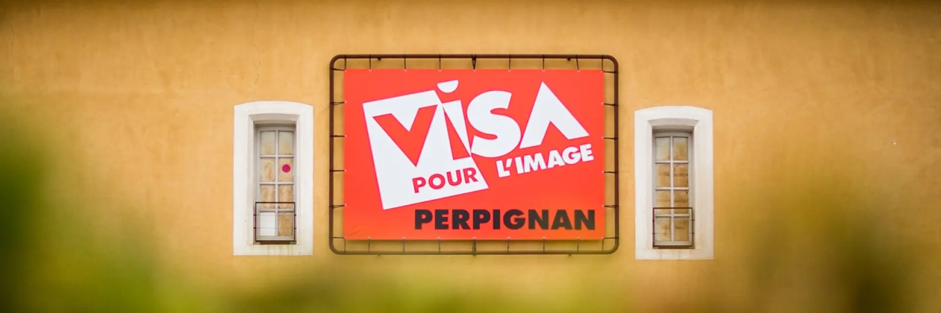 Panneau du festival Visa pour l’Image sur la façade d’un bâtiment à Perpignan.