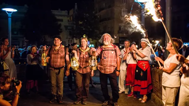 Porteurs de la flamme de la Saint-Jean arrivant à Perpignan, tenant des lanternes allumées entourés de spectateurs.