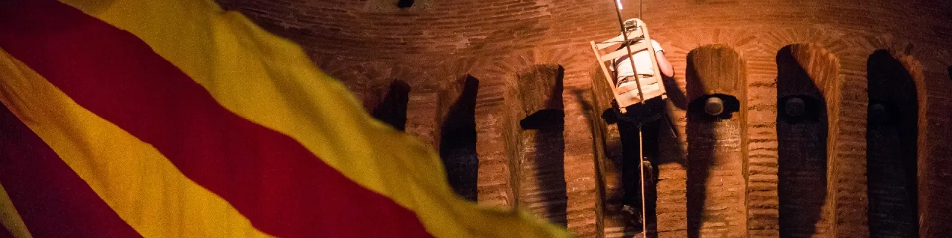 Descente de la flamme de la Saint-Jean depuis le Castillet à Perpignan, avec un drapeau catalan au premier plan.