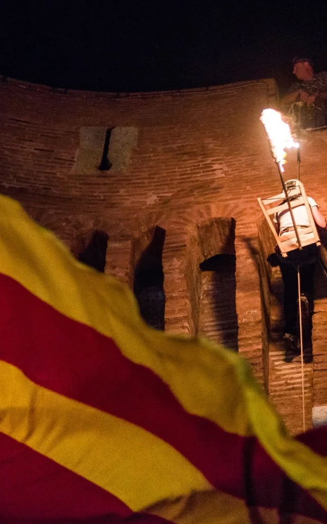 Descente de la flamme de la Saint-Jean depuis le Castillet à Perpignan, avec un drapeau catalan au premier plan.
