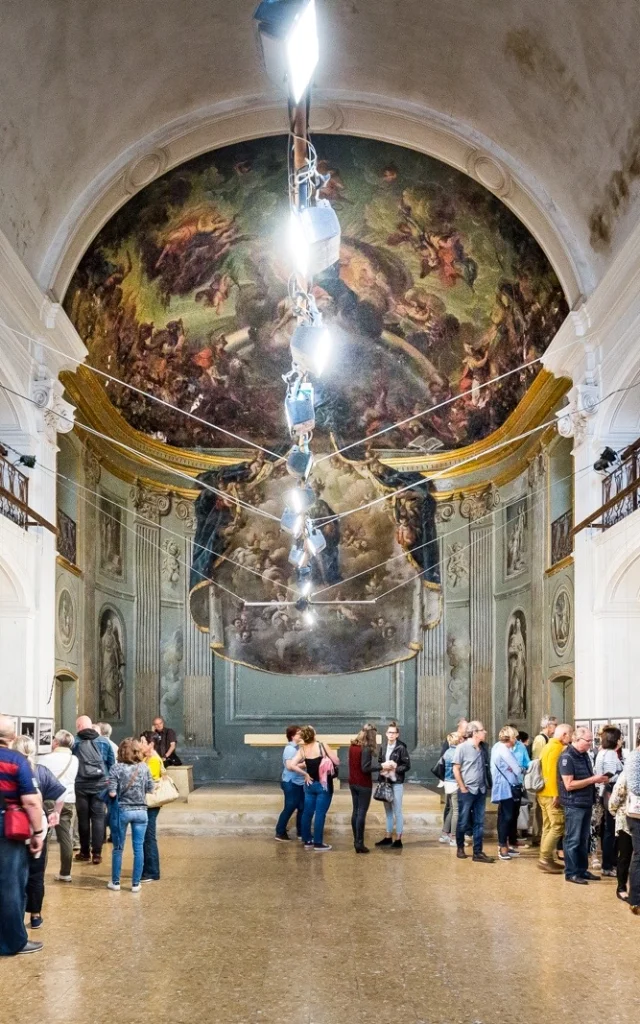 Visiteurs observant une exposition de photographies dans une ancienne chapelle lors du festival Visa pour l’Image à Perpignan.
