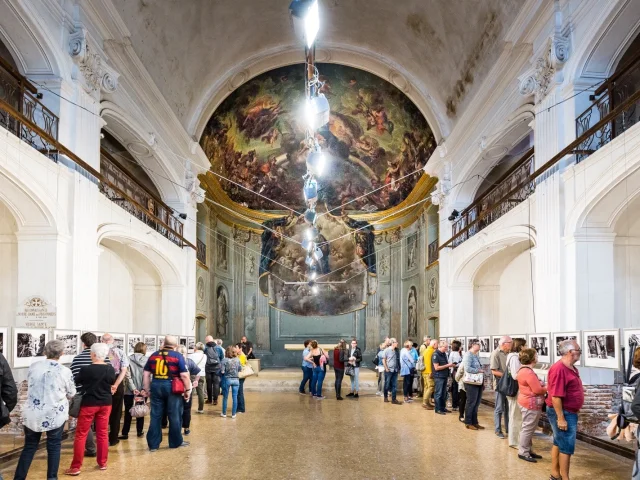 Visiteurs observant une exposition de photographies dans une ancienne chapelle lors du festival Visa pour l’Image à Perpignan.