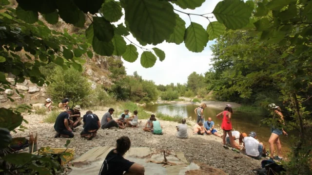 Groupe de visiteurs participant à un atelier préhistorique en plein air au bord de la rivière à Tautavel.