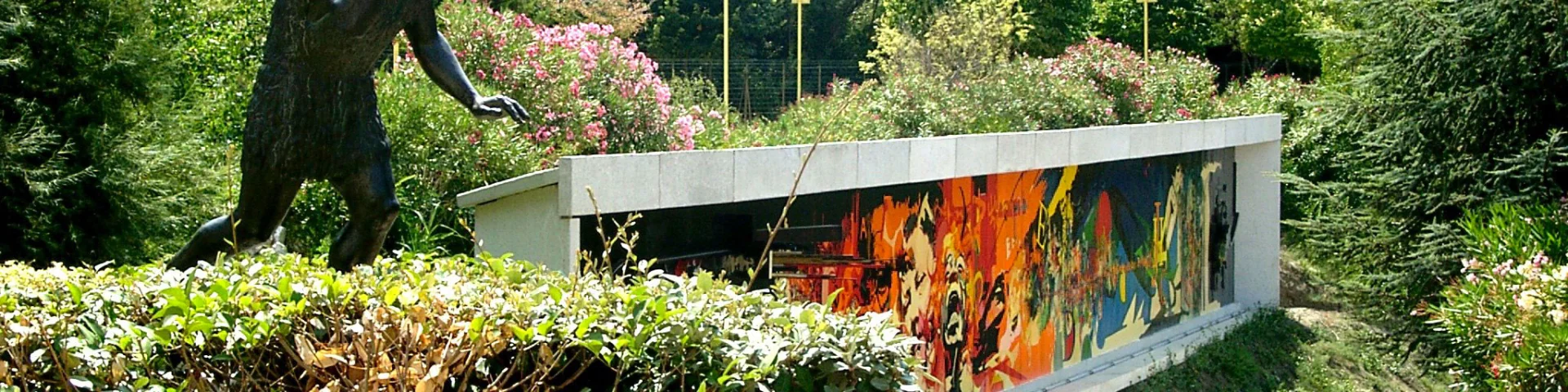 Statue préhistorique et façade colorée du musée de Préhistoire de Tautavel entourées de verdure.