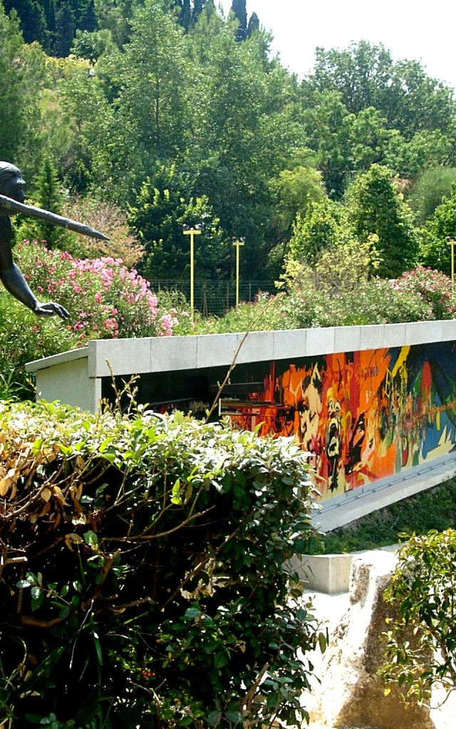 Statue préhistorique et façade colorée du musée de Préhistoire de Tautavel entourées de verdure.