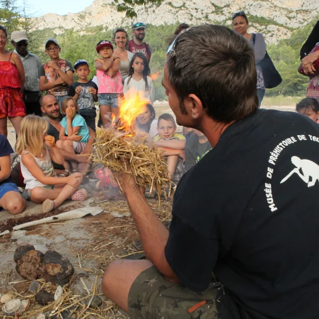 Animation préhistorique au musée de Tautavel : un animateur montre comment allumer un feu devant un groupe d’enfants.