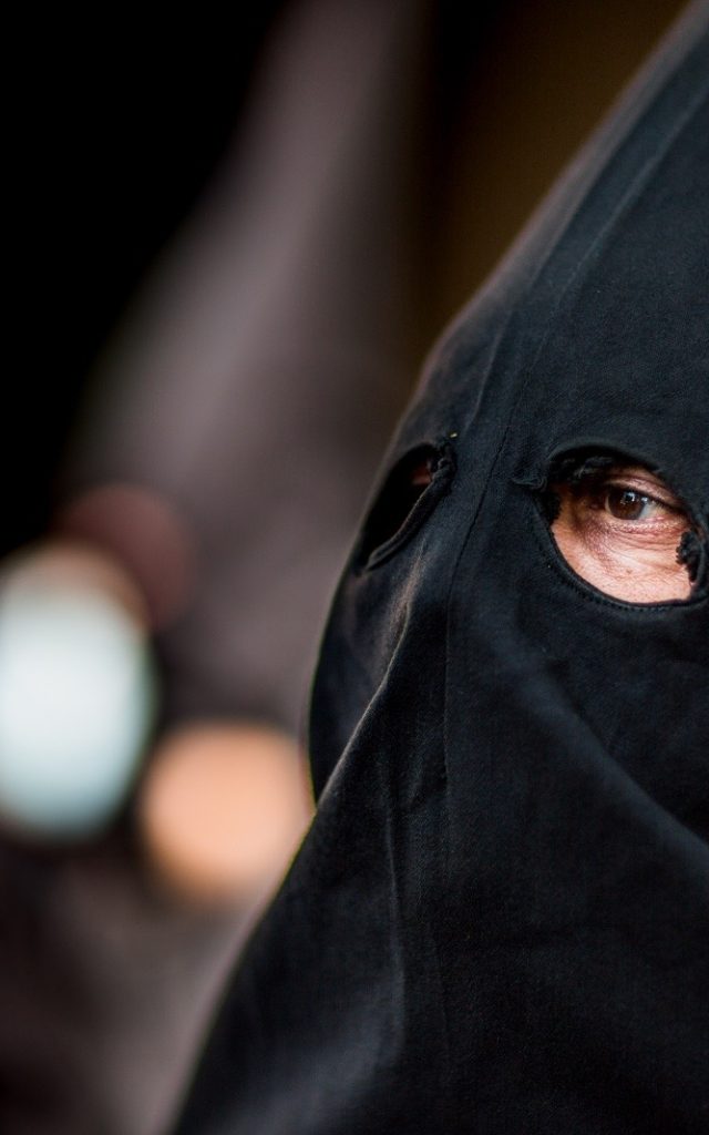Gros plan sur un pénitent vêtu d’une cagoule noire lors de la Procession de la Sanch à Perpignan.