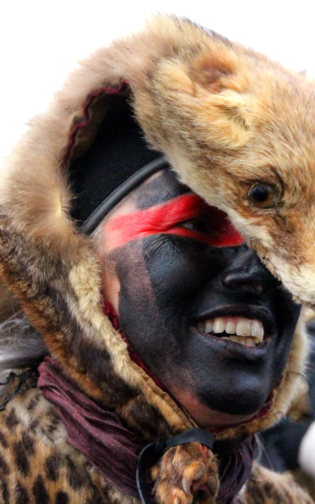 Participant de la Fête de l’Ours portant une peau d’animal sur la tête et un maquillage noir et rouge, symbole des traditions du Vallespir.