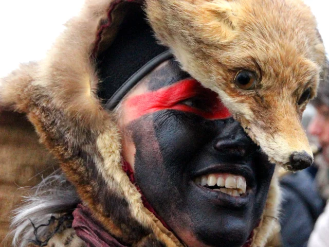 Participant de la Fête de l’Ours portant une peau d’animal sur la tête et un maquillage noir et rouge, symbole des traditions du Vallespir.