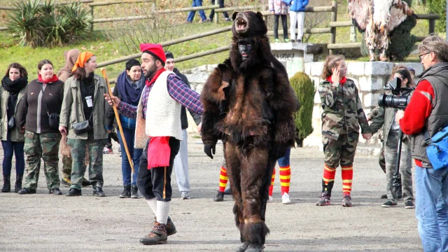 Personnage déguisé en ours accompagné d’un homme en tenue traditionnelle catalane pendant la Fête de l’Ours, sous le regard du public.