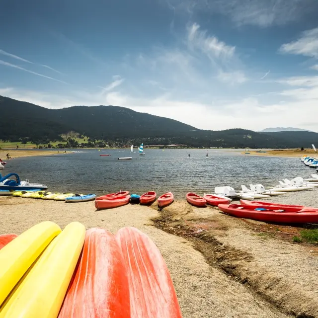 Activités nautiques sur la base du lac de Matemale en été, avec kayaks, pédalos et planches à voile au pied des montagnes du Capcir.