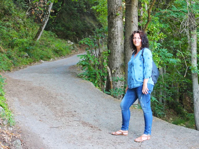 Personne marchant sur un sentier ombragé dans la forêt menant à l’abbaye Saint-Martin du Canigou.