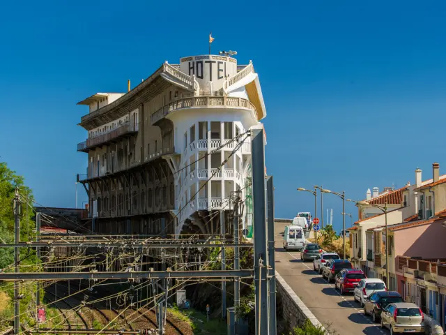 Vue sur l’hôtel du Belvédère du Rayon Vert, imposant bâtiment Art déco dominant les voies ferrées et la mer à Cerbère, sous un ciel bleu limpide.