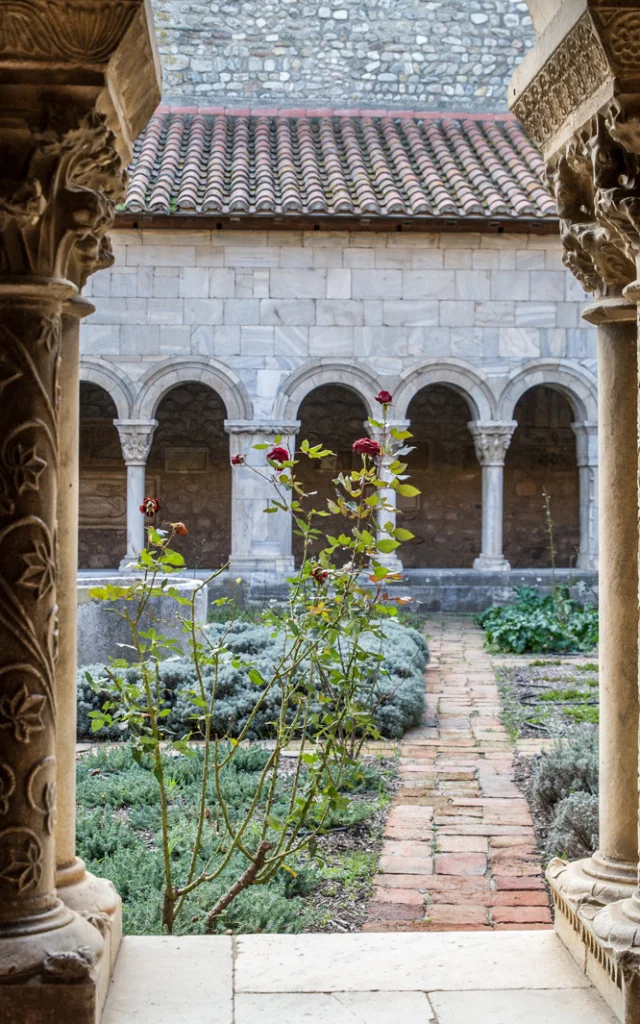 Vue du cloître roman avec ses colonnes sculptées et son jardin intérieur planté de lavandes et de rosiers.