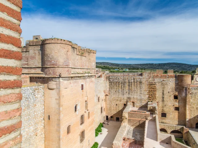 Vue intérieure du Fort de Salses, imposante forteresse en briques et pierre, sous un ciel bleu, avec les collines du Roussillon en arrière-plan.